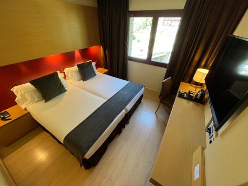 a hotel room with a large bed and a television at Wuau! Hotel Galanthus & Spa in Soldeu