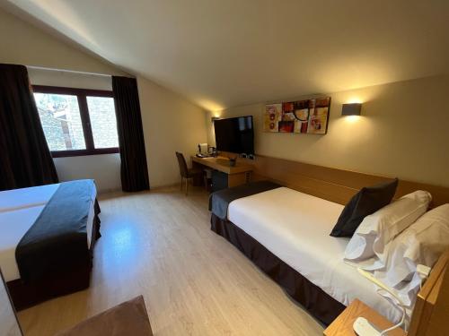 a hotel room with two beds and a desk at Wuau! Hotel Galanthus & Spa in Soldeu