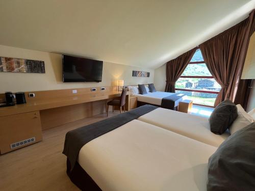 a hotel room with two beds and a flat screen tv at Wuau! Hotel Galanthus & Spa in Soldeu