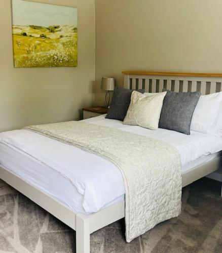 a bedroom with a large bed with white sheets and pillows at Hope Orchard En-Suite Rooms in Cheltenham