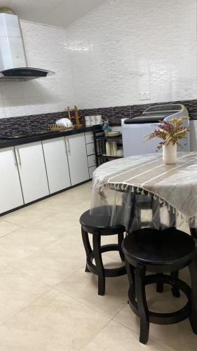 a kitchen with a table and two black chairs at The Deck Homestay & Event House in Jitra