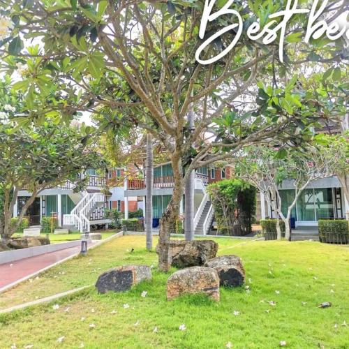 a tree with rocks in the grass in front of a building at Aura Samui Best Beach Hotel - SHA Plus in Lamai
