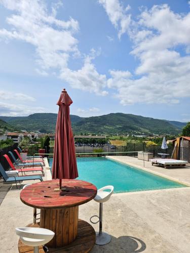 a table with a umbrella and chairs next to a pool at Le Coin Charmant - vue montagnes et jacuzzi privé in Privas
