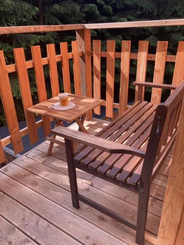 a wooden bench sitting on a wooden deck with a table at Apartmán Mariánská Hora in Albrechtice v Jizerských horách