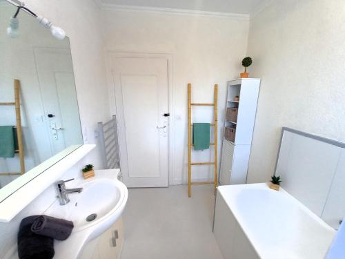 une salle de bain blanche avec un lavabo et un miroir dans l'établissement La Tremblade - MAISON mitoyenne en CENTRE-VILLE - CENTRE et PORT A PROXIMITE, à La Tremblade
