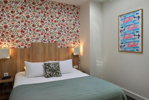 a bedroom with a bed with a floral wall at Logis Hôtel Restaurant Maison Voltaire in Amboise