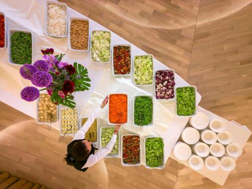a woman standing in front of a table with bowls of food at Hotel Apollo Terme in Montegrotto Terme