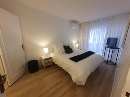 une chambre avec un grand lit blanc et une fenêtre dans l'établissement Appartement 2 pièces carré d or Les Floralies, à Antibes