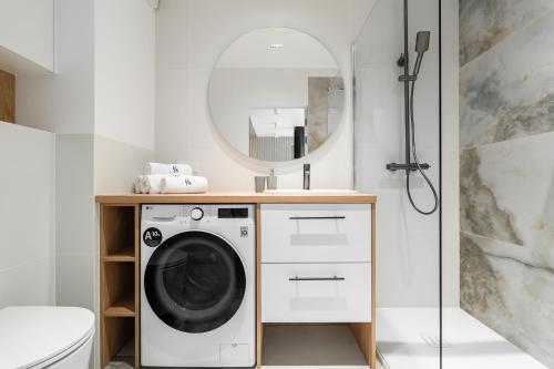 a bathroom with a washing machine and a mirror at Sarbinove City Apartments in Sarbinowo