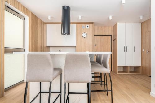 a kitchen with white cabinets and a bar with stools at Sarbinove City Apartments in Sarbinowo