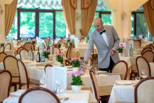 a man in a tuxedo standing in a dining room at Hotel Apollo Terme in Montegrotto Terme