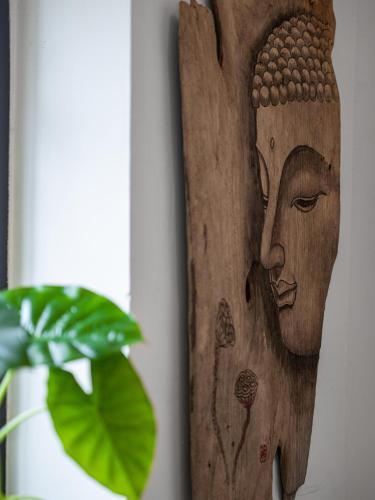a wooden head on a wall next to a plant at Guilin Tranquil Peaks Retreat by Reed Flute Cave in Guilin