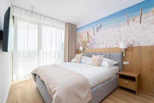 a bedroom with a bed and a painting of the beach at Sarbinove City Apartments in Sarbinowo