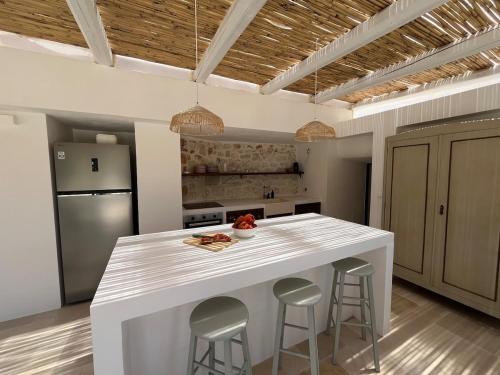a kitchen with a white island with bar stools at Trullo La Rosmarina in San Michele Salentino