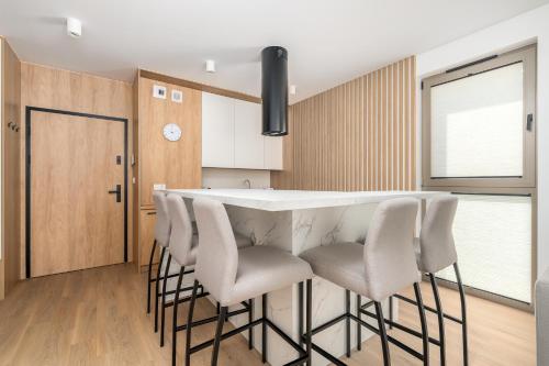 a kitchen with a white counter and stools at Sarbinove City Apartments in Sarbinowo