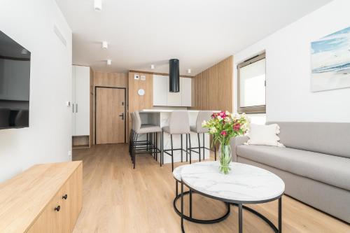 a living room with a couch and a table with flowers at Sarbinove City Apartments in Sarbinowo