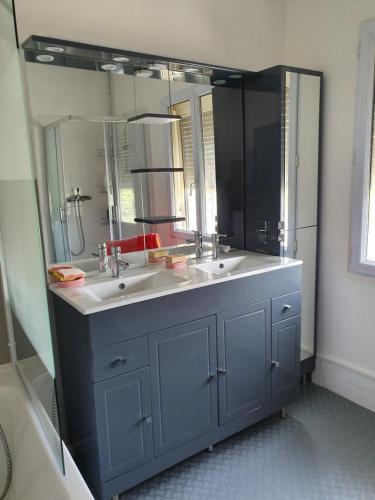 une salle de bain avec deux lavabos et un grand miroir dans l'établissement Charmant appartement dans maison Familiale, à Beaucaire