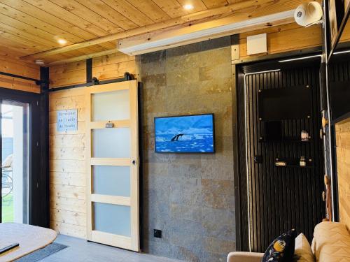 a room with a door and a tv on a wall at La Cachette du Domaine du Moulin avec son spa privé en option in Saint-Laurent-dʼAndenay
