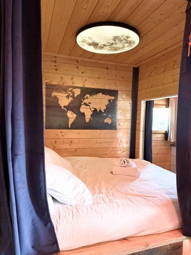 a bed in a wooden room with a map on the wall at La Cachette du Domaine du Moulin avec son spa privé en option in Saint-Laurent-dʼAndenay