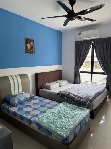 two beds in a room with a ceiling fan at KH Water Park Manhattan Condo Ipoh Homestay in Kampong Pinji