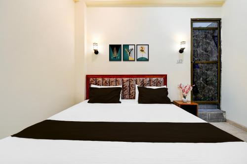 a bedroom with a large white bed with black pillows at Hotel O SRS Inn Guest House in Gorakhpur