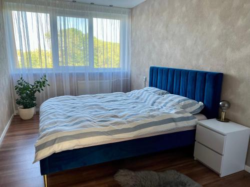a bed with a blue headboard in a bedroom at SORD apartment in Liepāja