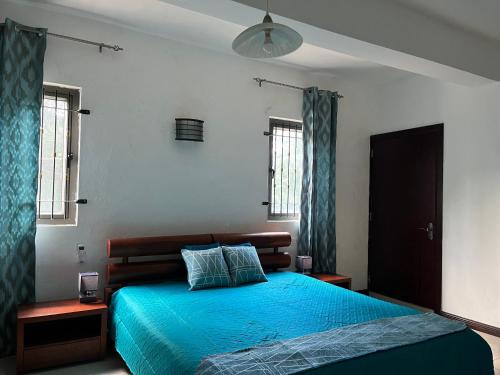 a bedroom with a bed with blue sheets and windows at Fortuna Beach in Flic-en-Flac