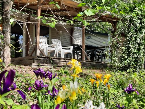 un porche avec deux chaises blanches et des fleurs dans l'établissement camping le pontet, à Saint-Martin-dʼArdèche