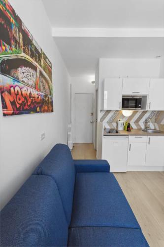 un salon avec un canapé bleu et une cuisine dans l'établissement Le Citadin - Hypercentre - Cosy - Shopping - WIFI, à Nice