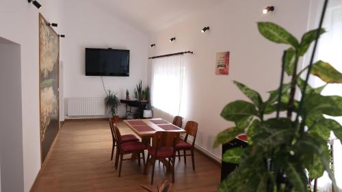a dining room with a table and chairs and a tv at CASA Bia in Haţeg