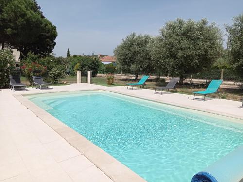 une piscine avec des chaises bleues et une piscine dans l'établissement Charmant appartement dans maison Familiale, à Beaucaire