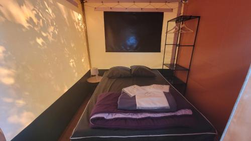Cette chambre comprend un lit avec une chemise. dans l'établissement Camping La Fritillaire, à Savigny-en-véron