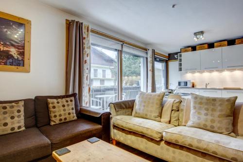 un salon avec un canapé et des chaises et une cuisine dans l'établissement Minuit appartement - Snow and Trek, à Morzine