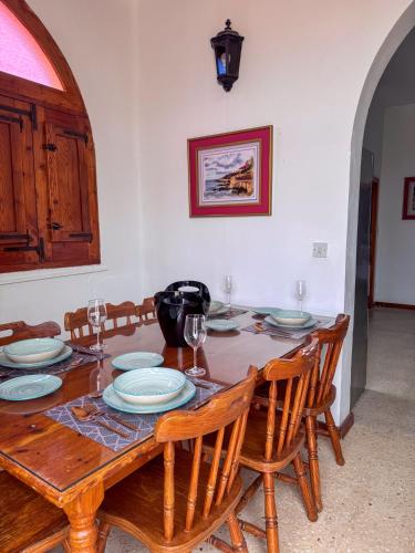 a dining room table with plates and wine glasses at Tal Jordan Complex in Għarb
