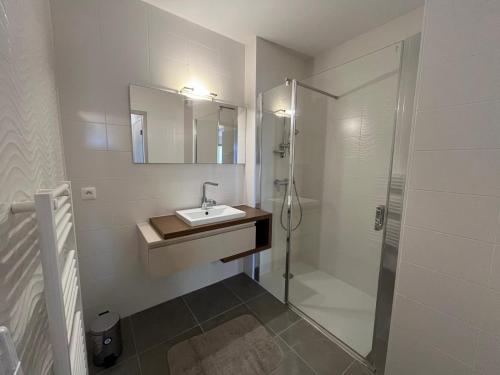 une salle de bain blanche avec un lavabo et une douche dans l'établissement Gaul, à Valras-Plage