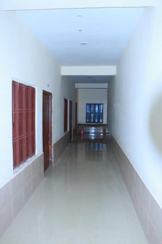 an empty room with white walls and a hallway with windows at Shri Jagannath Dham in Naimishāranya