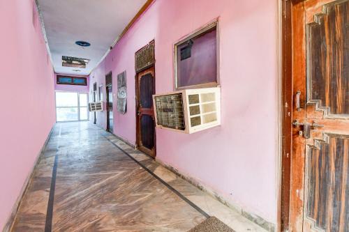 an empty hallway with a pink wall and an open door at Hotel O Muchhad 75 Hotel & Restaurant in Etāwah