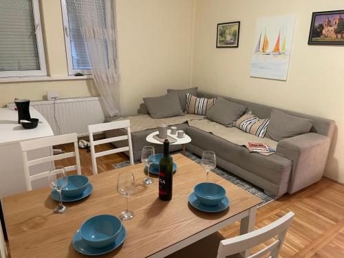 Una sala de estar con un sofá y una mesa con copas de vino. en SkyBreak Apartment, en Ledine