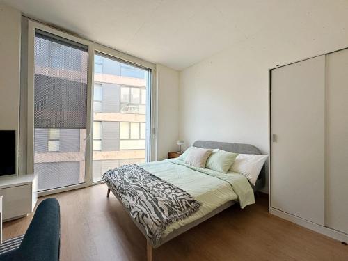 a bedroom with a bed and a large window at Studio dans les haut de Lausanne 06 in Le Mont-sur-Lausanne