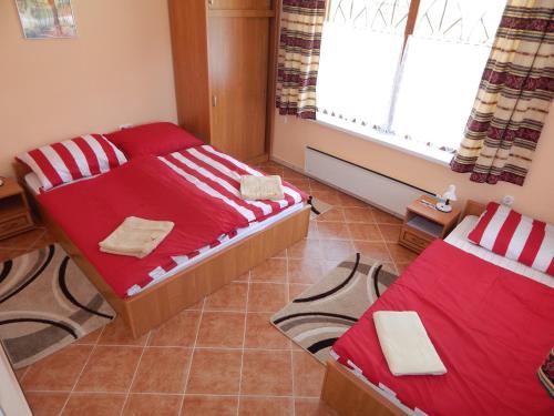 a bedroom with two beds and a window at Tündér Szálló Eplény in Eplény