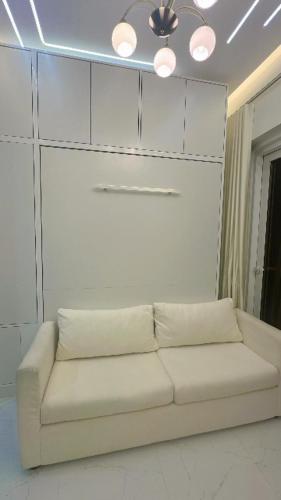 a white couch in a living room with a ceiling at Designer 1BR I Golf View I Comfortably Sleeps 4 in Dubai
