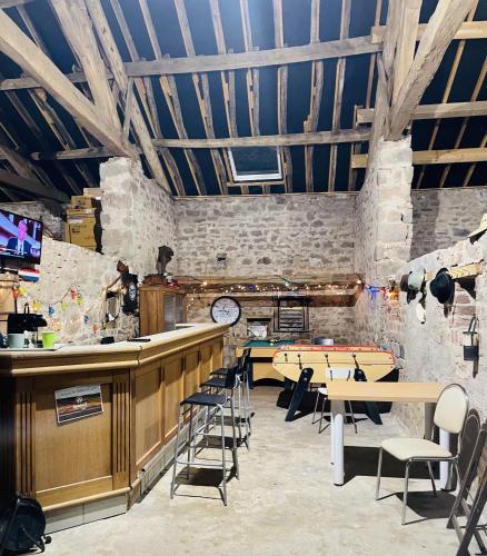 a restaurant with a bar and tables and chairs at La Cachette du Domaine du Moulin avec son spa privé en option in Saint-Laurent-dʼAndenay
