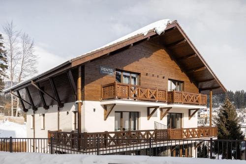 a large wooden house with a balcony in the snow at PENTA by Alfinio in Sinaia