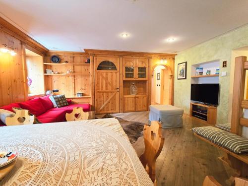 a living room with a bed and a red couch at Essenze di Bosco - Alpine Stay Apartments in Predazzo