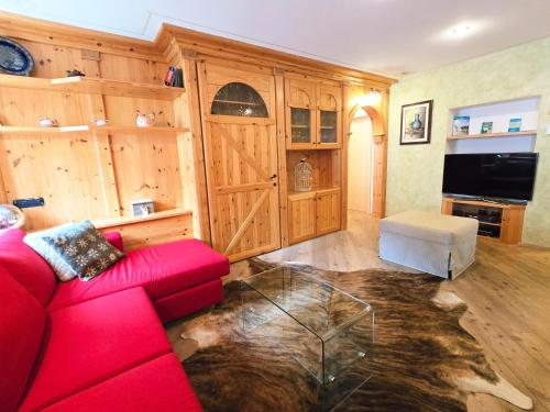 a living room with a red couch and a tv at Essenze di Bosco - Alpine Stay Apartments in Predazzo