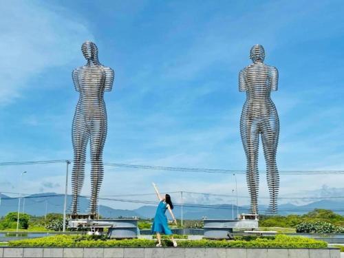 a woman walks past two large steel statues of two women at Arena jakovi condotel in Cam Ranh International Airport