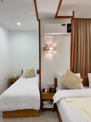 two beds in a hotel room with white sheets at Palm Tbilisi Boutique Hotel in Tbilisi City