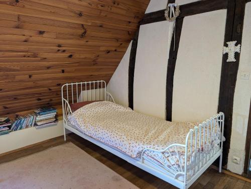 un lit dans une chambre avec un mur en bois dans l'établissement Maison de campagne, à Fondettes