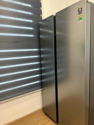 a stainless steel refrigerator in a kitchen next to a window at Chuỗi căn hộ dịch vụ Vinhomes Gardenia Mỹ Đình in Hanoi