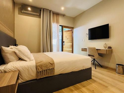 a bedroom with a bed and a desk and a television at The Symbol in Fourways
